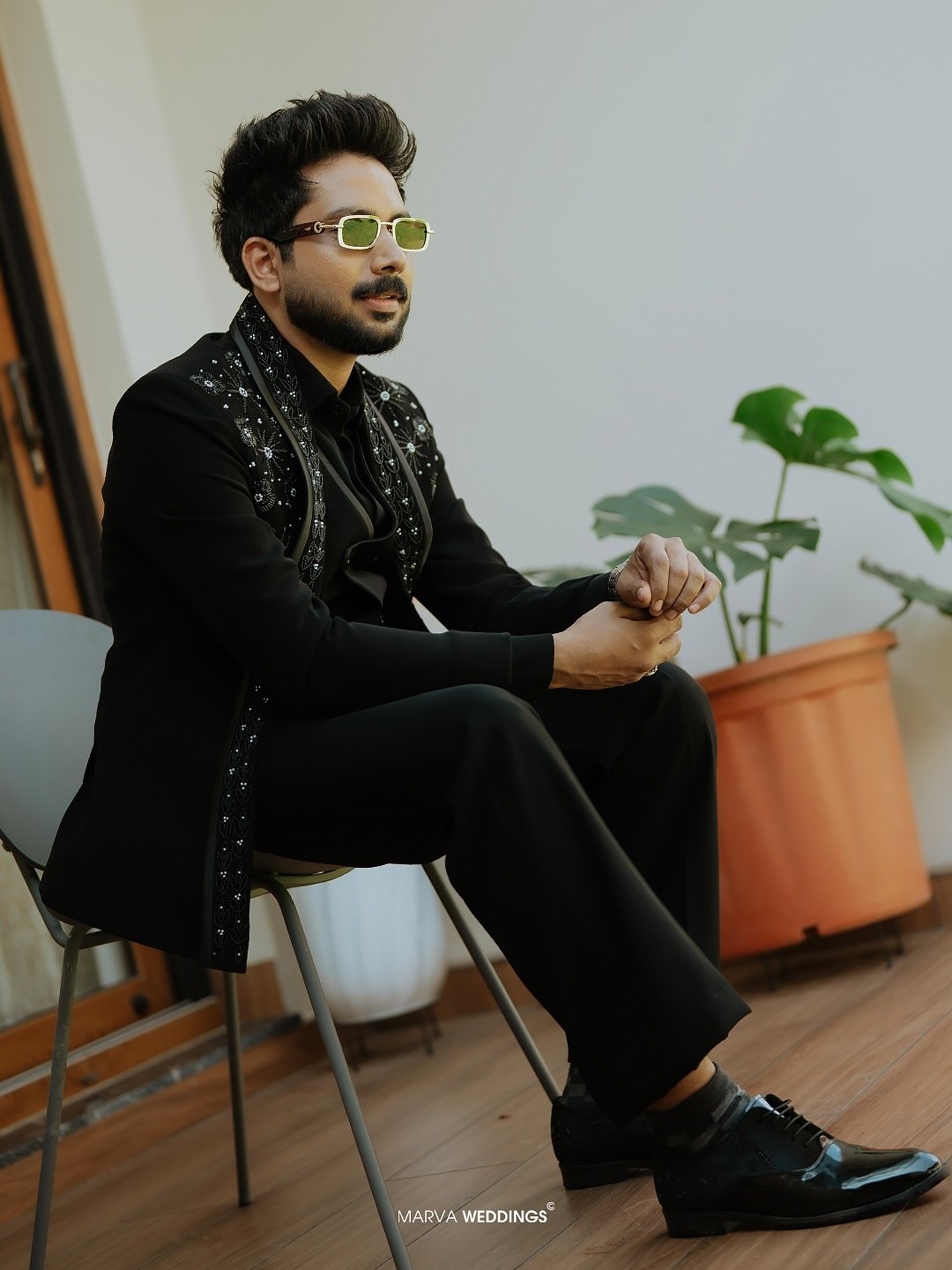 Groom in an embroidered black suit and sunglasses